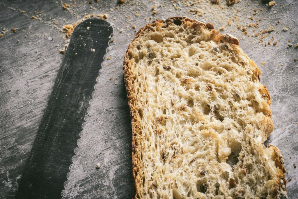 A slice of brown bread next to a bread knife