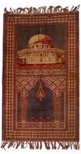 A woven prayer mat decorated with patterns and a mosque pictured on a blank white background