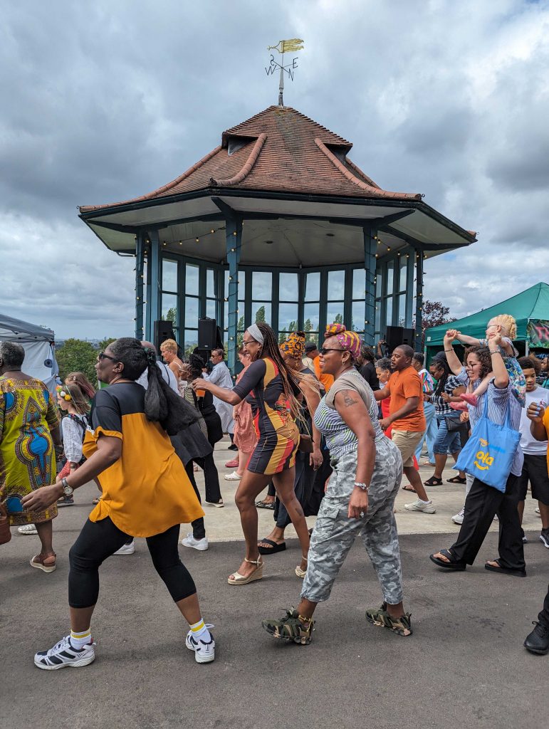 Group of people dancing in front of the Horniman Bandstand
